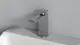 Wascharmatur von Ideal Standard in Chrom mit einem modernen, kantigen Design, montiert auf einem weißen Waschbecken vor einer grauen Wand.
